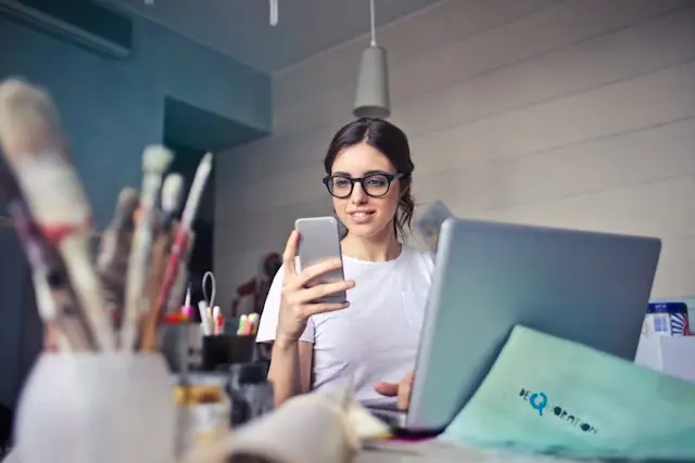 mujer con telefono movil y laptop